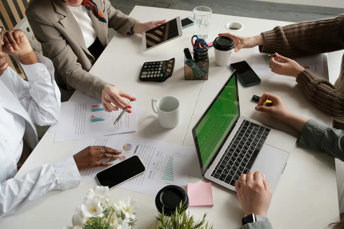 A casual marketing team meeting around a laptop with coffee